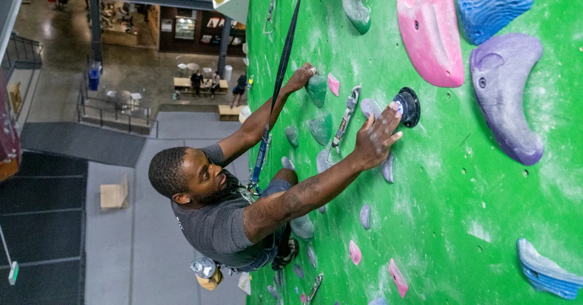 Ein Kletterer nutzt das TRUBLUE iQ+ Catch-and-Hold Selbstsicherungsgerät an einer Indoor-Kletterwand