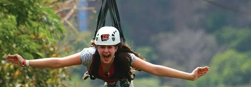 Bezoeker aan een zipline met focus op de afdaling over een open landschap