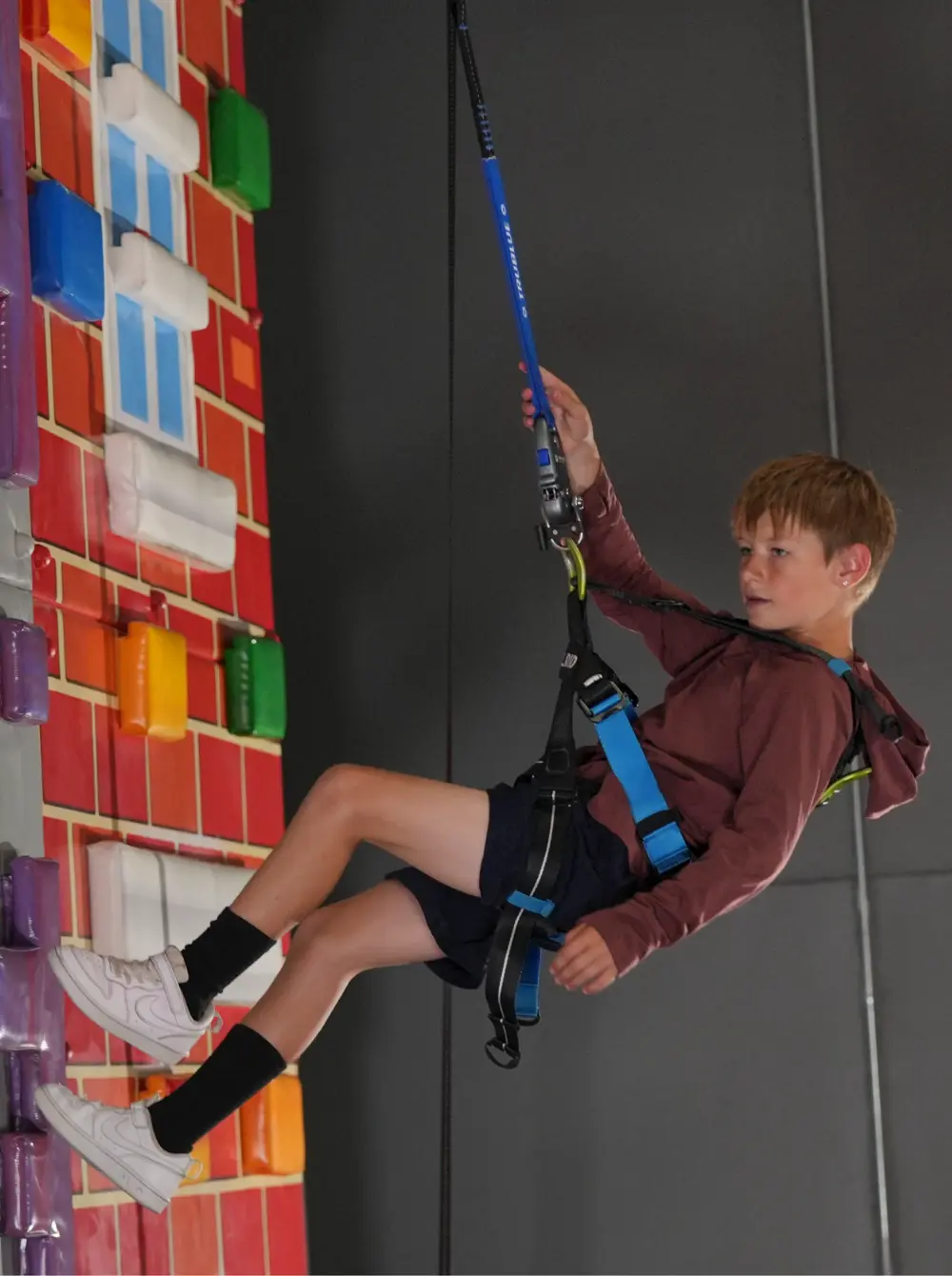 Een grote indoor klimmuur waarbij meerdere routes tegelijkertijd gebruikt worden dankzij auto belays