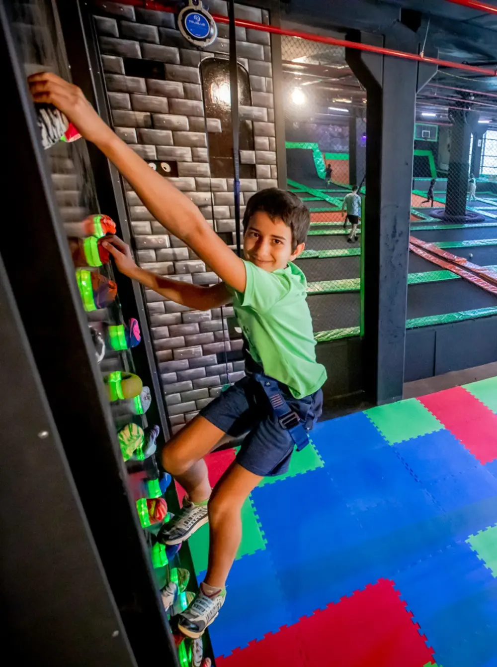 Kinder klettern sicher an einer FEC Kletterwand mit TRUBLUE Selbstsicherungsgeräten